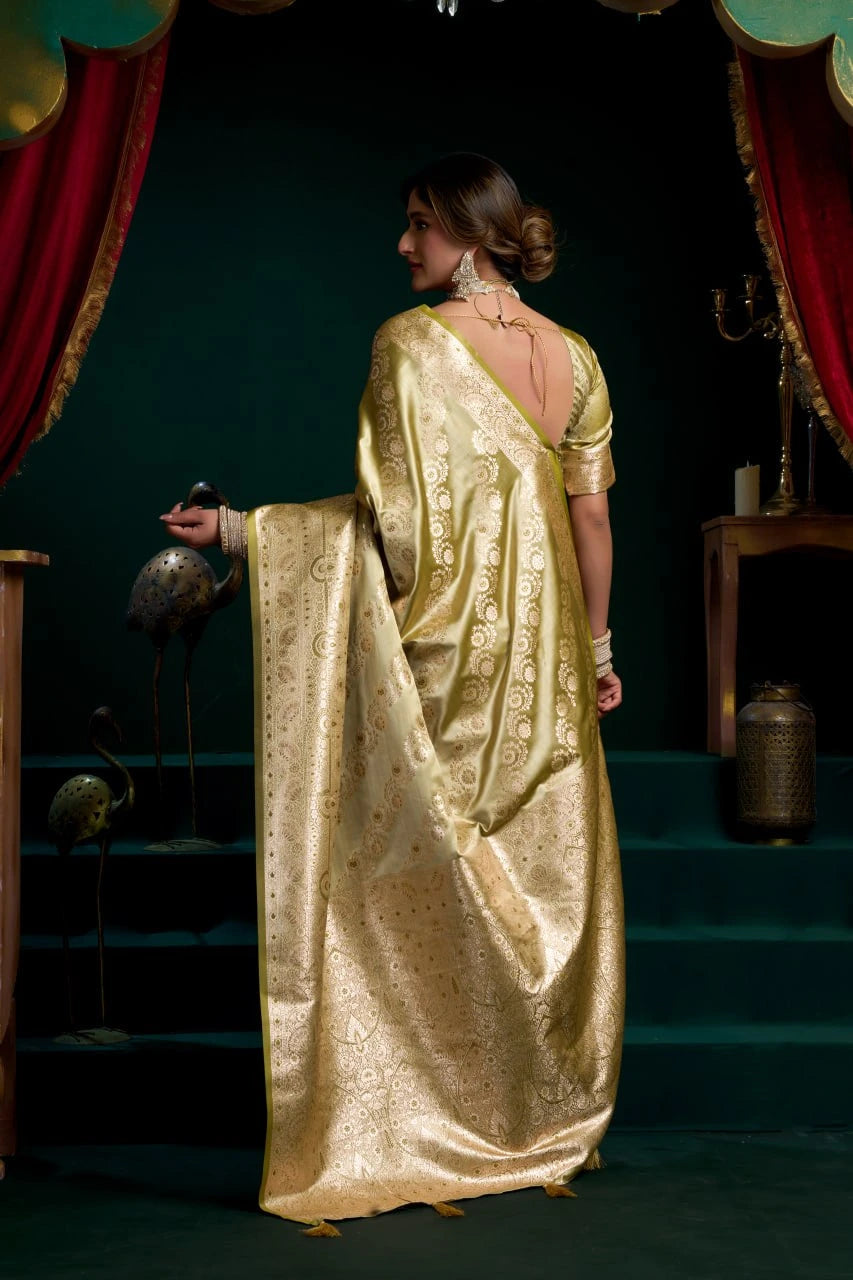 Woman in a gold saree standing on a stage with red curtains.