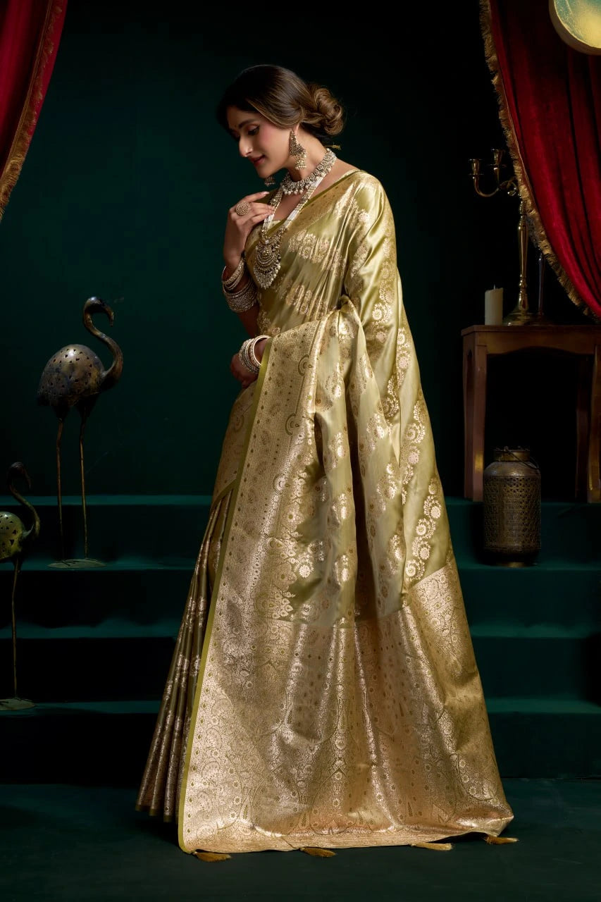 Woman in a gold saree standing in a dimly lit room with red curtains.