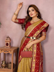 Woman wearing a red and gold saree with jewelry against a pink background