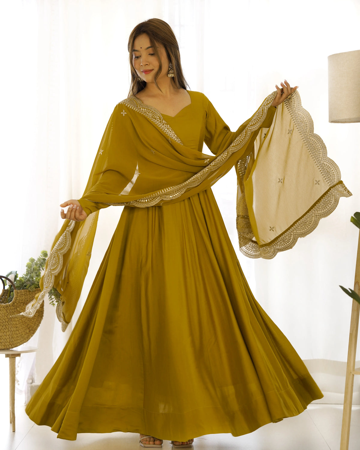 Woman wearing a mustard yellow traditional outfit with a matching dupatta indoors.