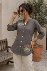 Gray cotton short kurti with pink and yellow floral bouquet print, model smiling outdoors paired with white trousers and gold accessories