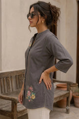 Gray floral print short kurti side profile view, model standing near terracotta pot outdoors, showing 3/4 sleeve and hem detail