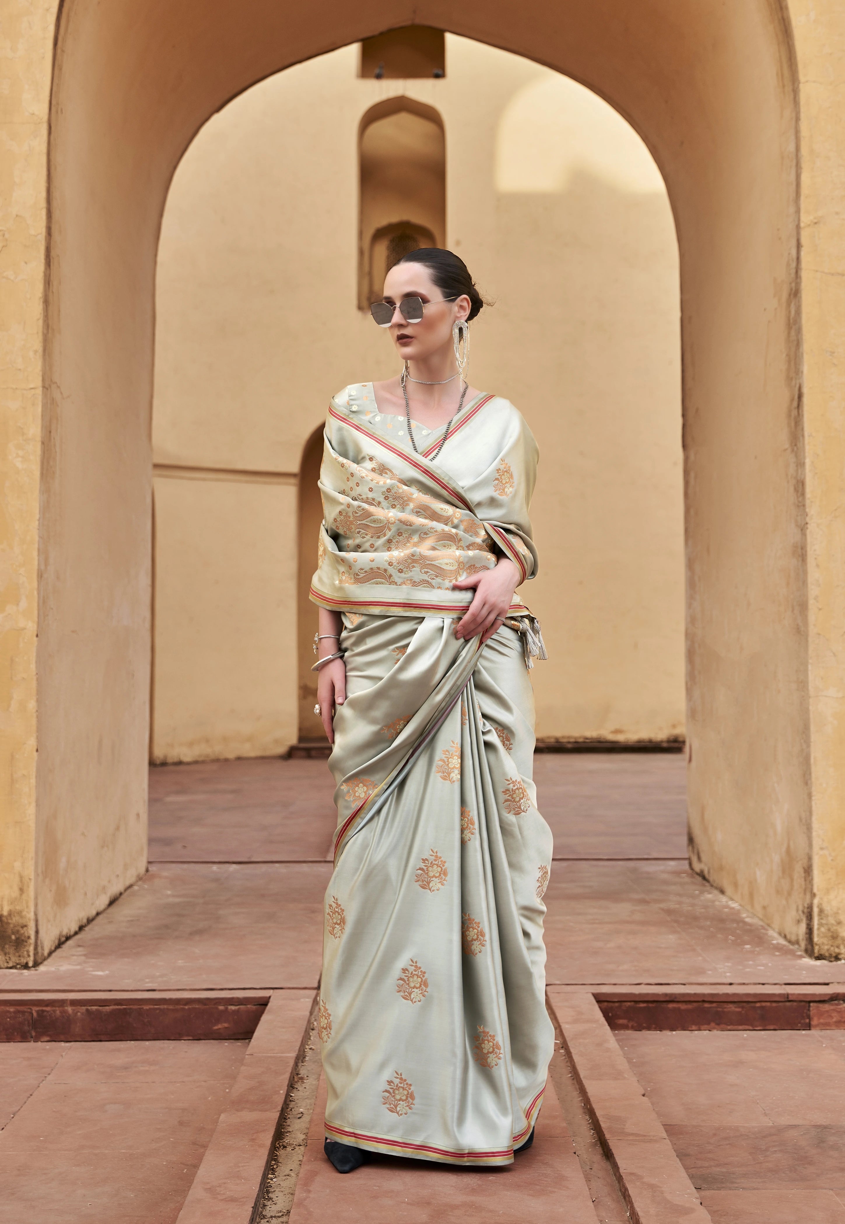 Woman in a saree standing in front of an archway