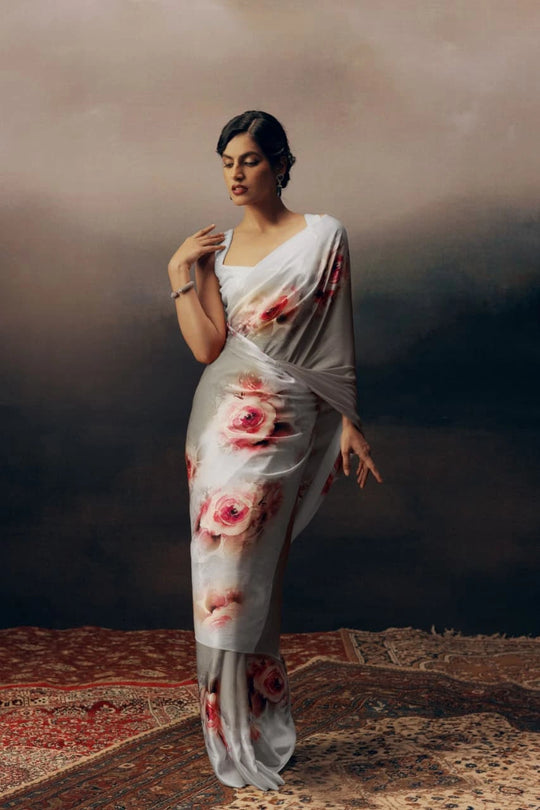 Woman wearing a floral saree against a dark background