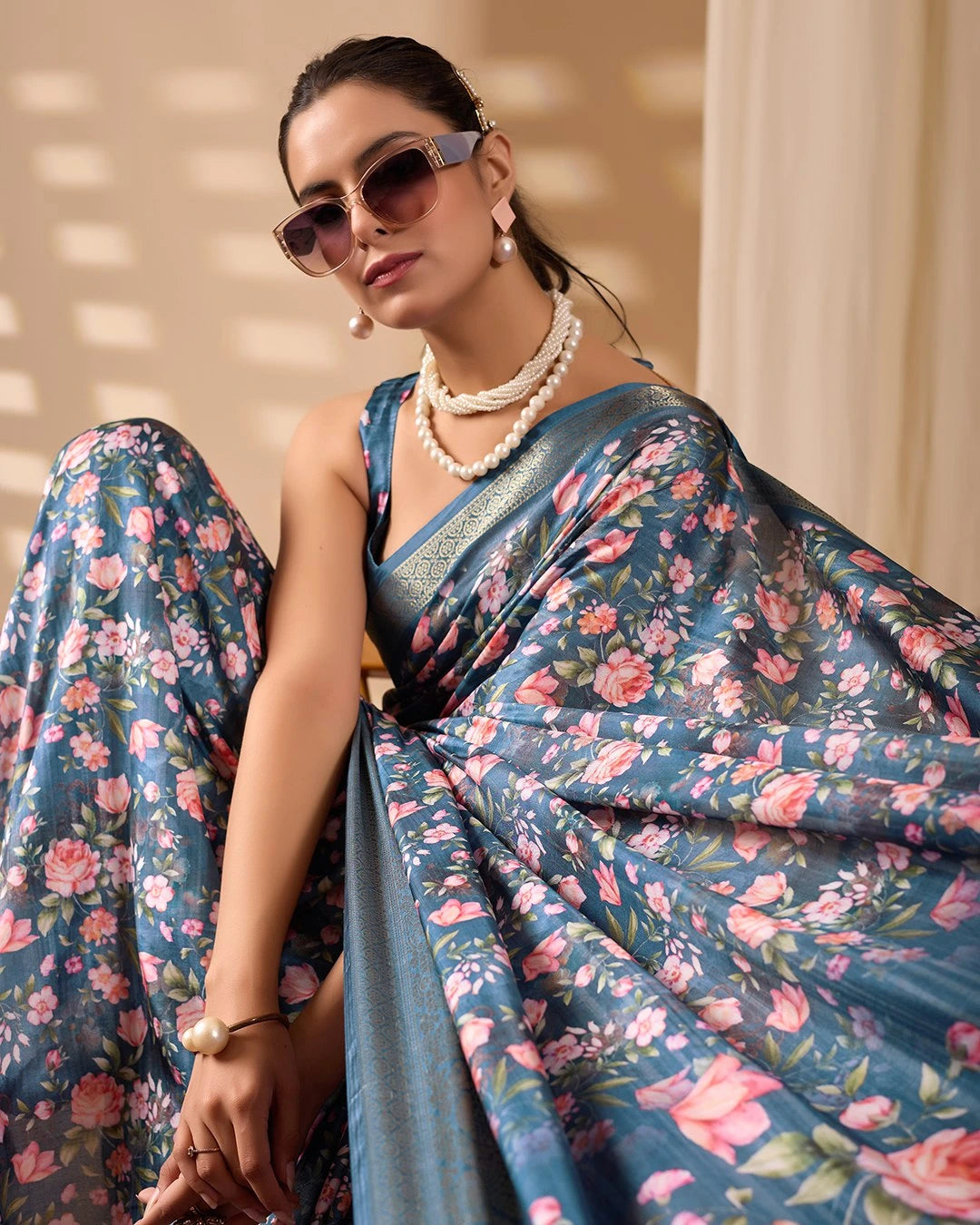 Woman wearing a floral saree with sunglasses and jewelry indoors.