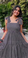 Woman wearing a black and white striped dress with bow straps outdoors.