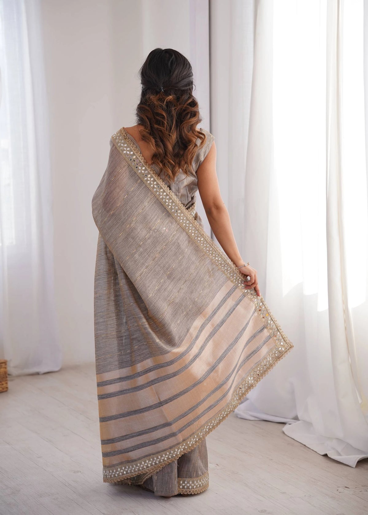 Woman wearing a traditional saree with a white curtain background