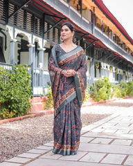 Woman in a traditional saree standing on a pathway with greenery and a building in the background