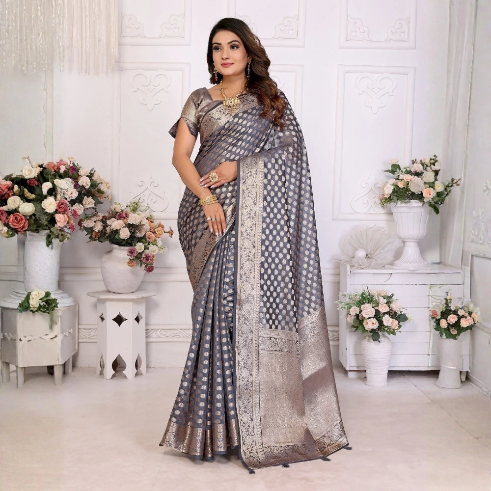 Woman in a saree standing in a decorated room with floral arrangements.