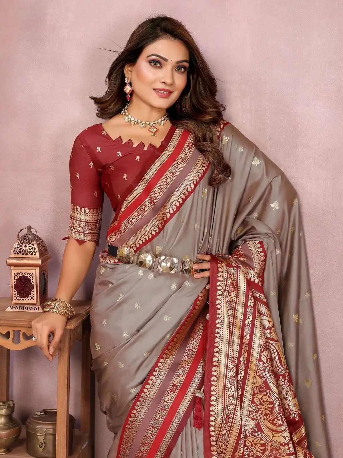 Woman wearing a traditional saree with a maroon and gray color scheme against a pink background