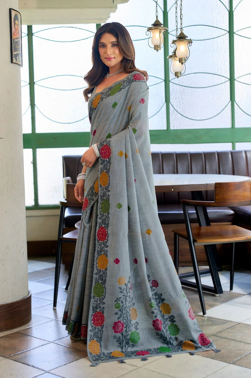 Woman wearing a gray saree with colorful floral patterns in an indoor setting.