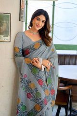 Woman wearing a gray saree with colorful patterns in an indoor setting.