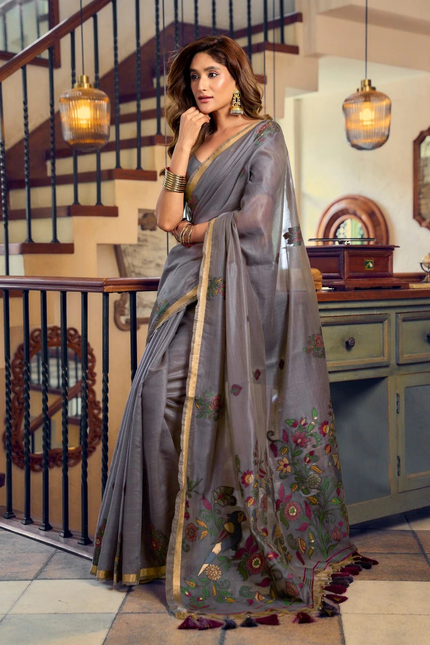 Woman in a gray saree with floral patterns indoors