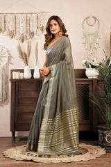 Woman in a gray saree standing in a room with decorative elements.