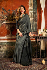 Woman in a dark green saree standing in an ornate room with classical decor.