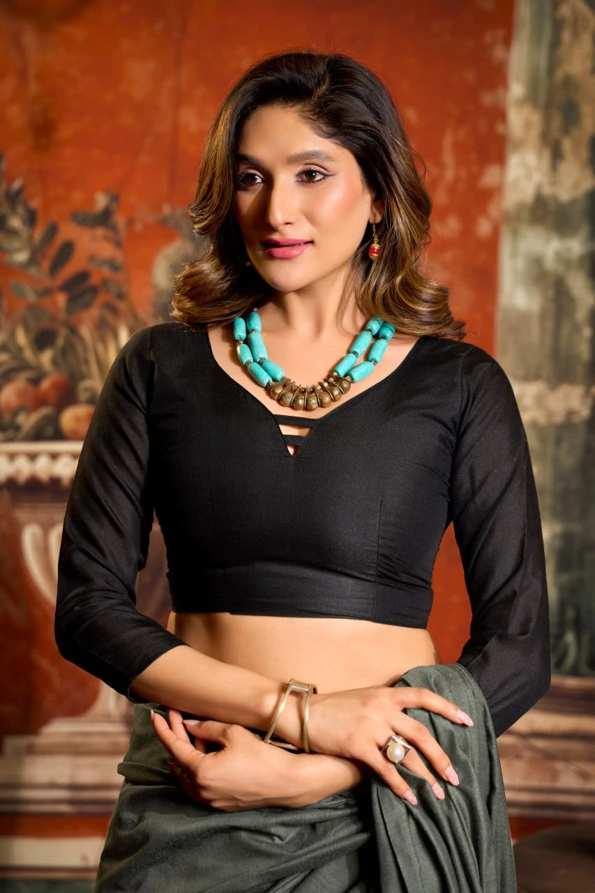 Woman wearing a black top and green skirt with a textured wall background