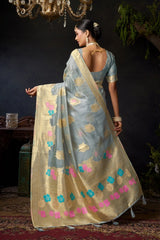 Woman in a traditional saree with floral patterns in a dimly lit room.