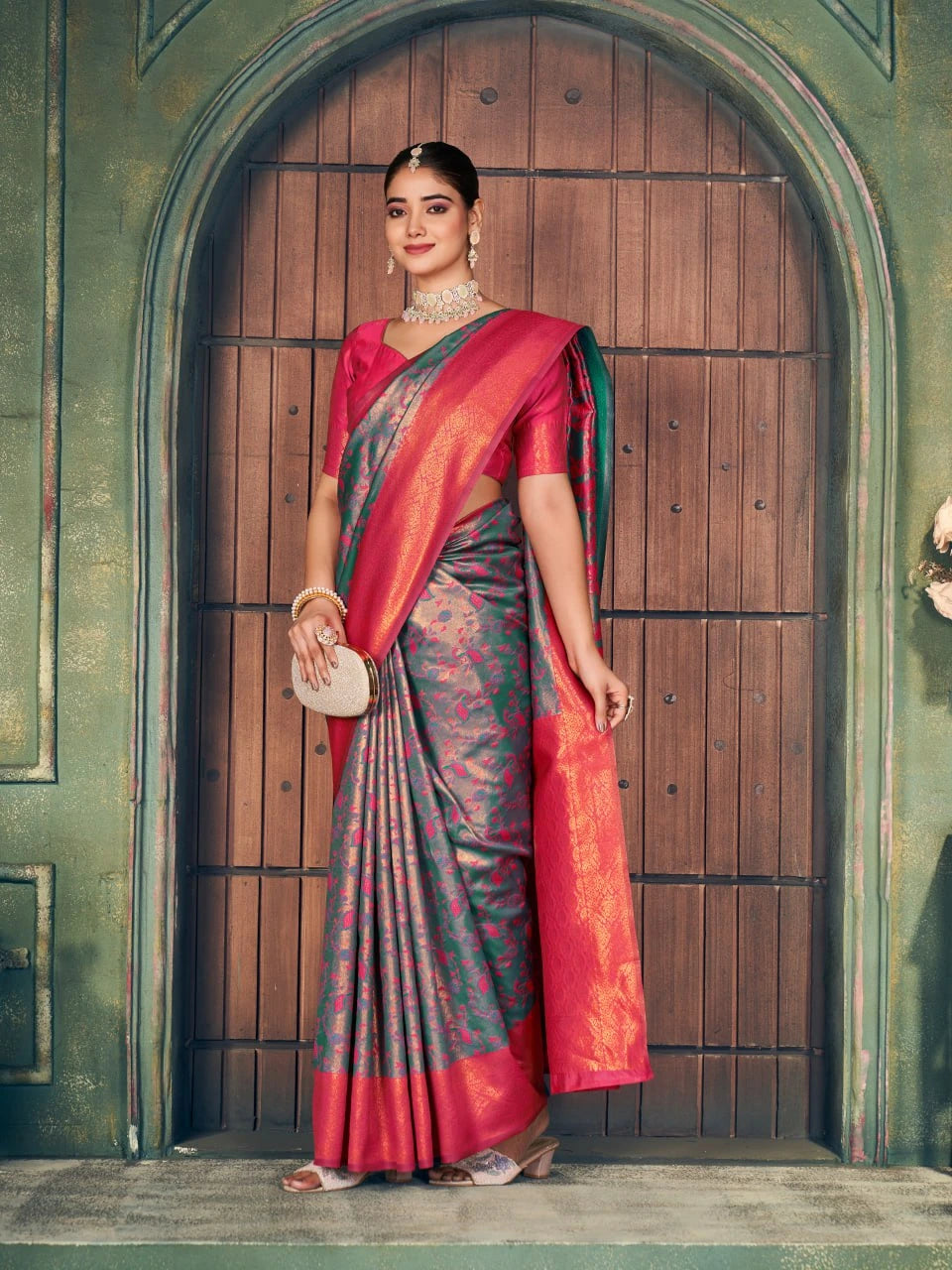 Woman in a traditional saree standing in front of a wooden door.