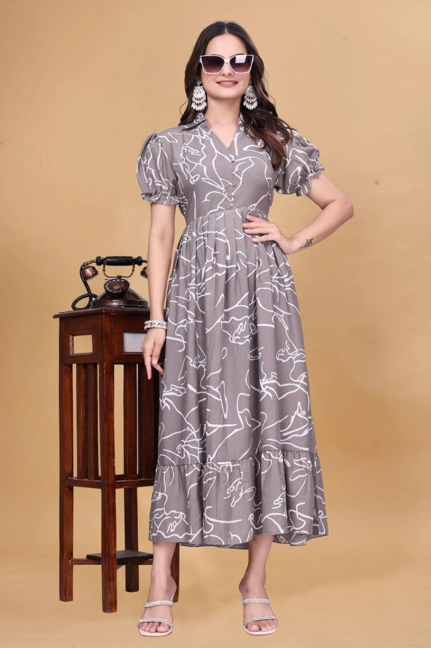 Woman wearing a gray patterned dress with sunglasses and earrings, standing against a beige background.