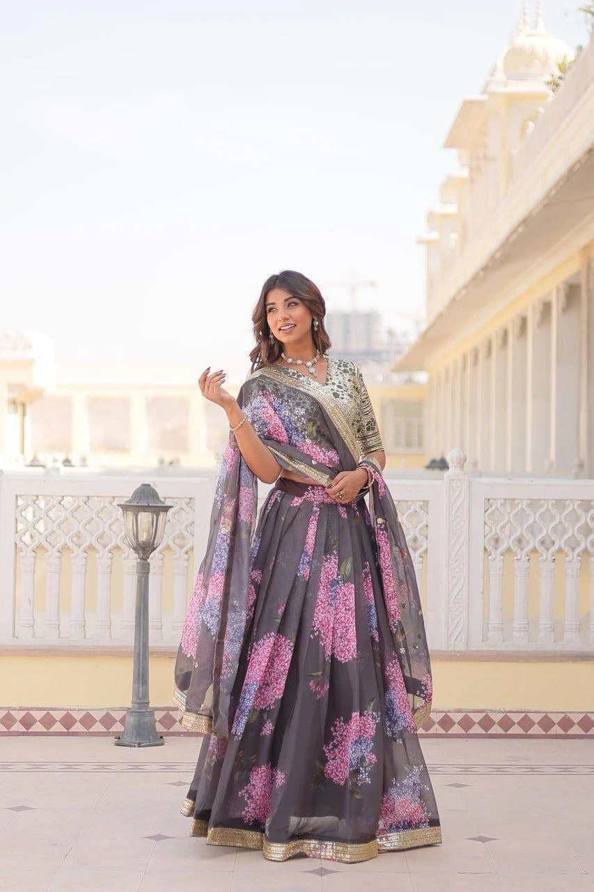 Woman in a floral saree standing in front of a traditional building.