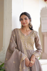 Woman wearing a gray traditional outfit with gold embroidery indoors.
