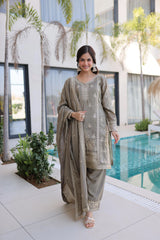 Woman in a traditional outfit standing by a pool with plants and a building in the background