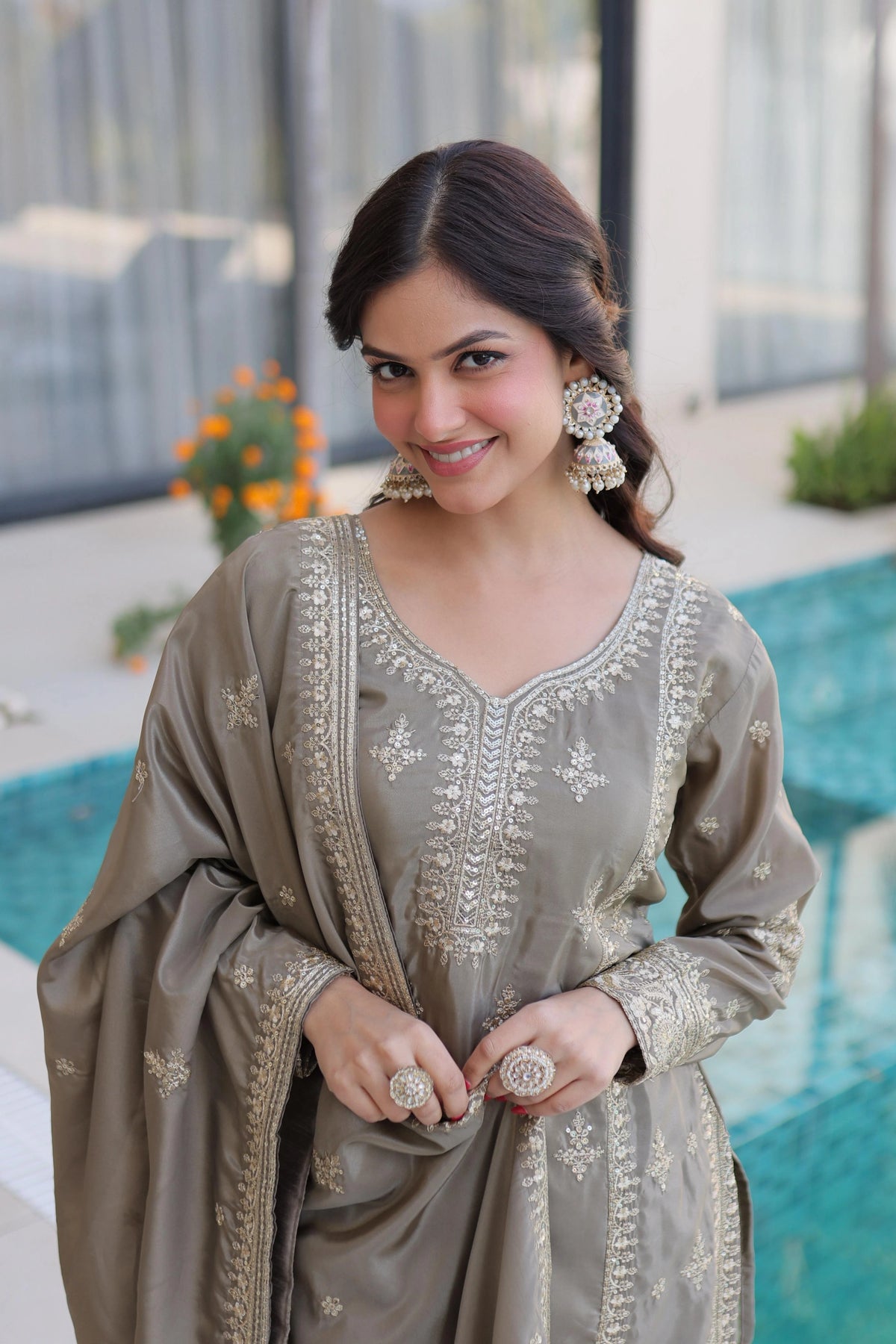 Woman in a traditional outfit with intricate designs, standing by a pool.