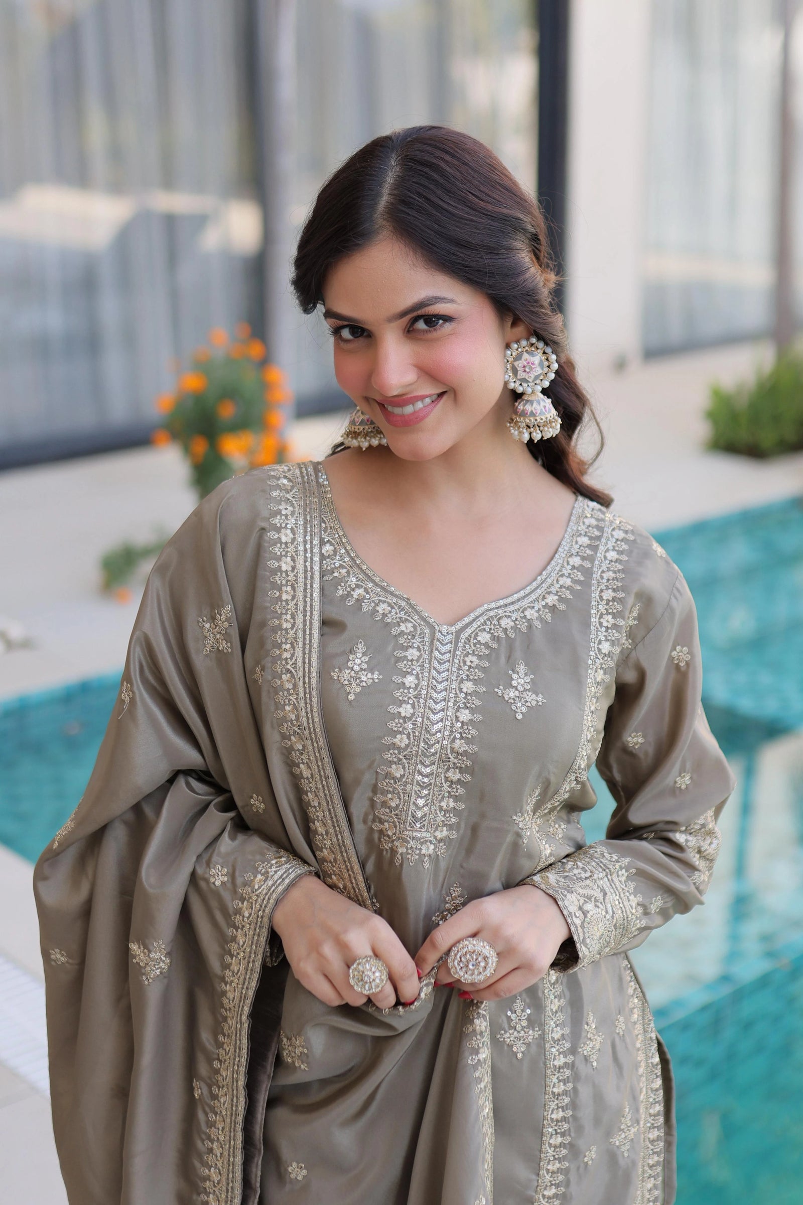 Woman in a traditional outfit with intricate designs, standing by a pool.