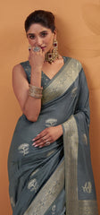 Woman wearing a gray saree with gold embroidery on a beige background