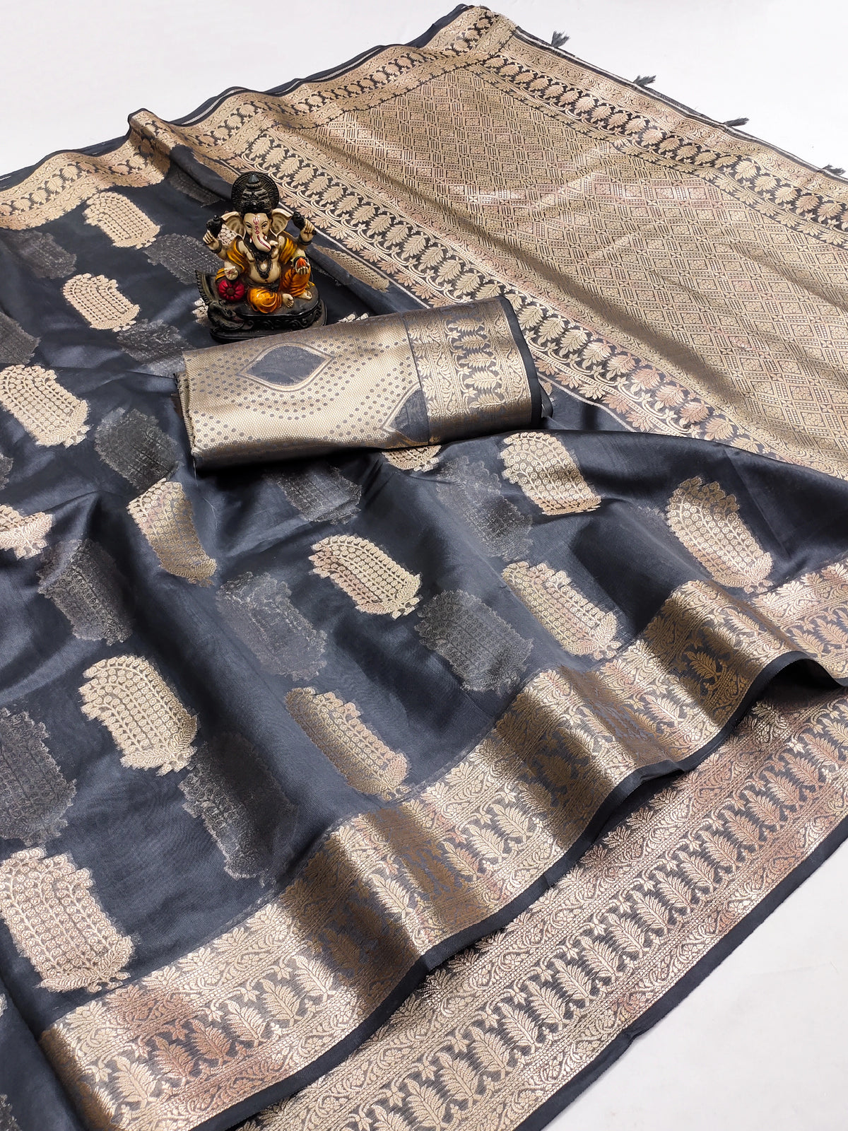 Black and gold saree with a decorative item on a white background