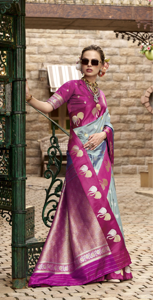 Woman in a vibrant purple saree with a light blue blouse, standing outdoors.