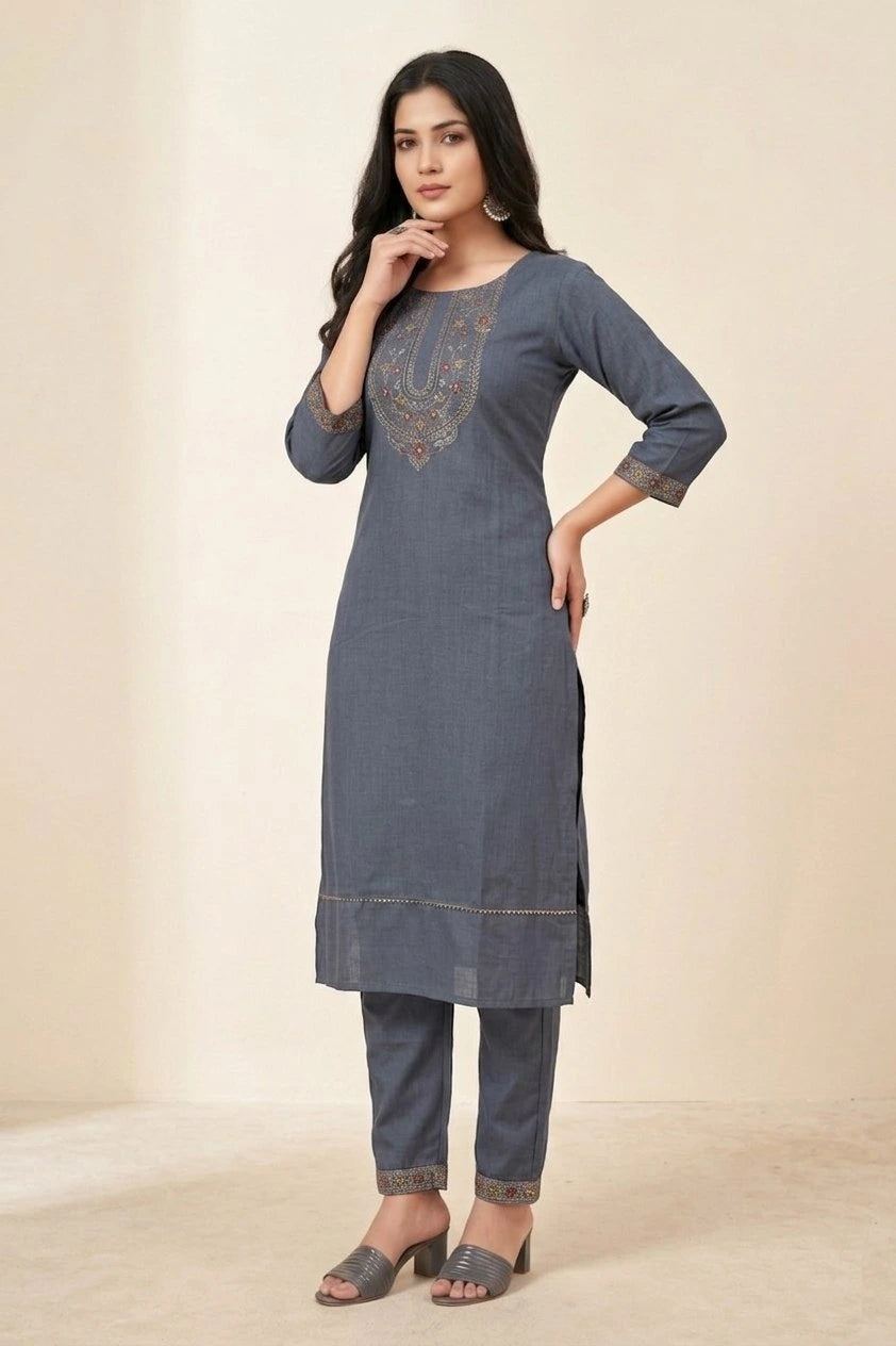 Woman wearing a blue denim outfit with intricate embroidery on a beige background