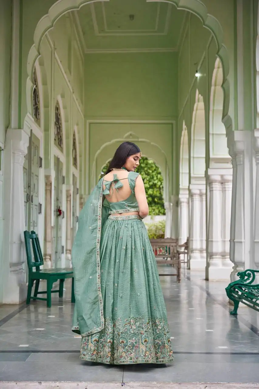 Back view of green thread embroidered lehenga showing fancy bow-tie back choli and dupatta drape