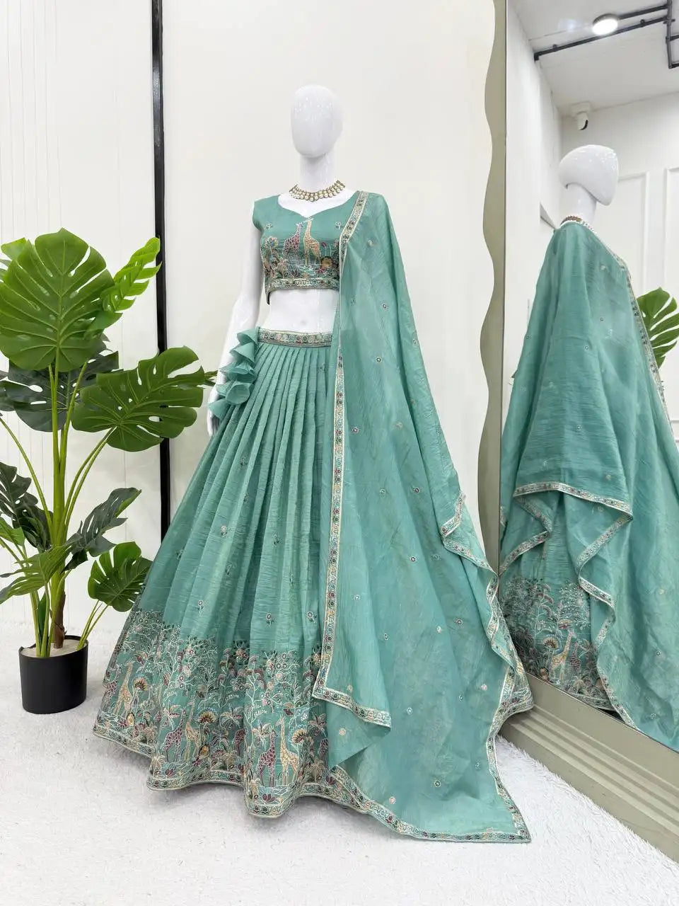 Full mannequin view of green thread embroidered lehenga showing ruffle waist and wide Mughal animal border