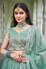 Portrait of model wearing green gold crush lehenga showing V-neck choli with giraffe motif embroidery