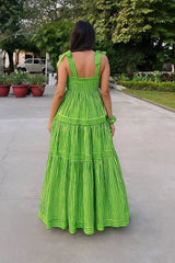 Woman wearing a green dress with white stripes walking on a sidewalk.