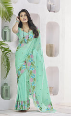 Woman wearing a light green saree with floral patterns in a minimalistic setting.