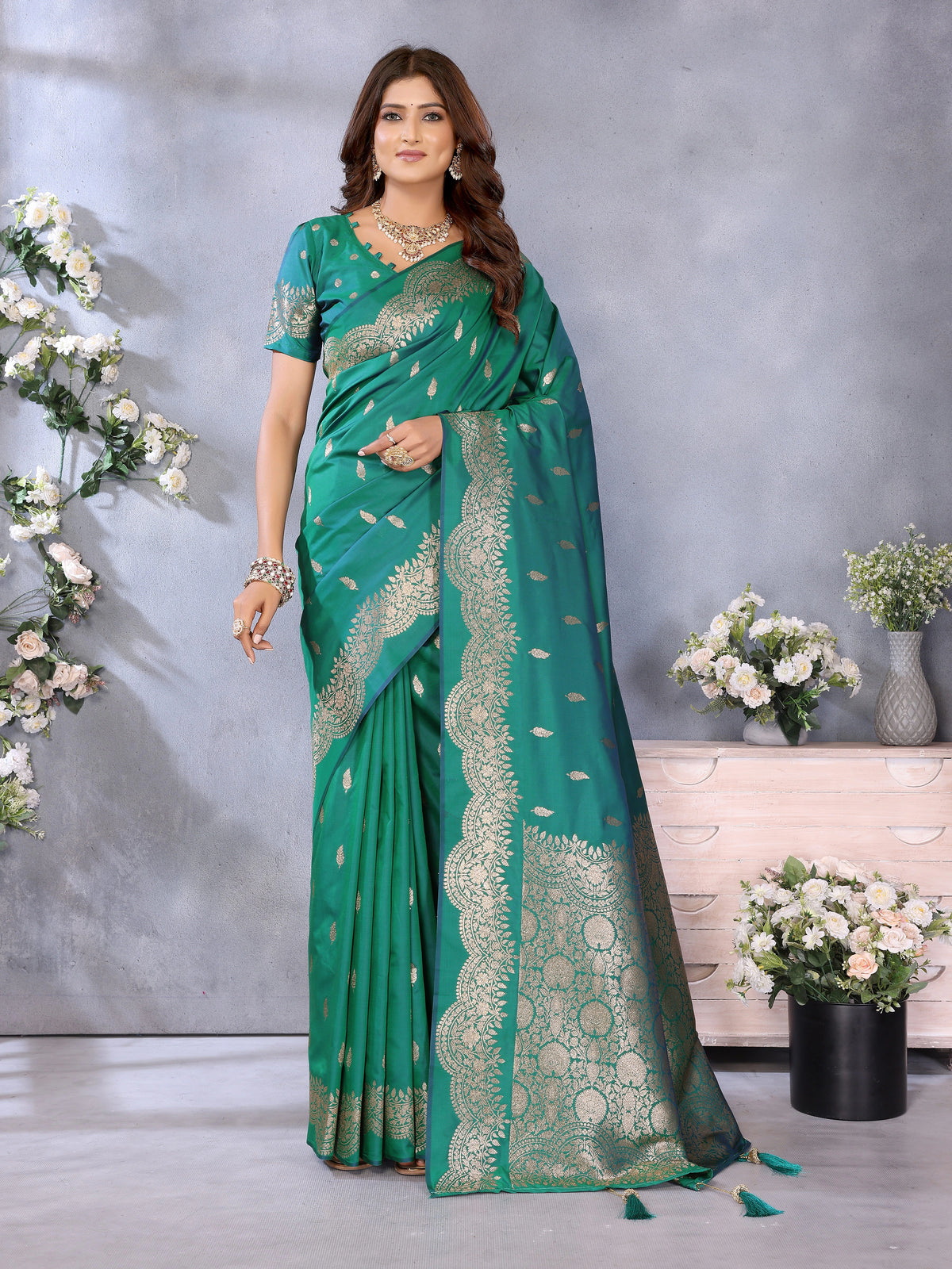 Woman wearing a green saree with white patterns in a decorated indoor setting.