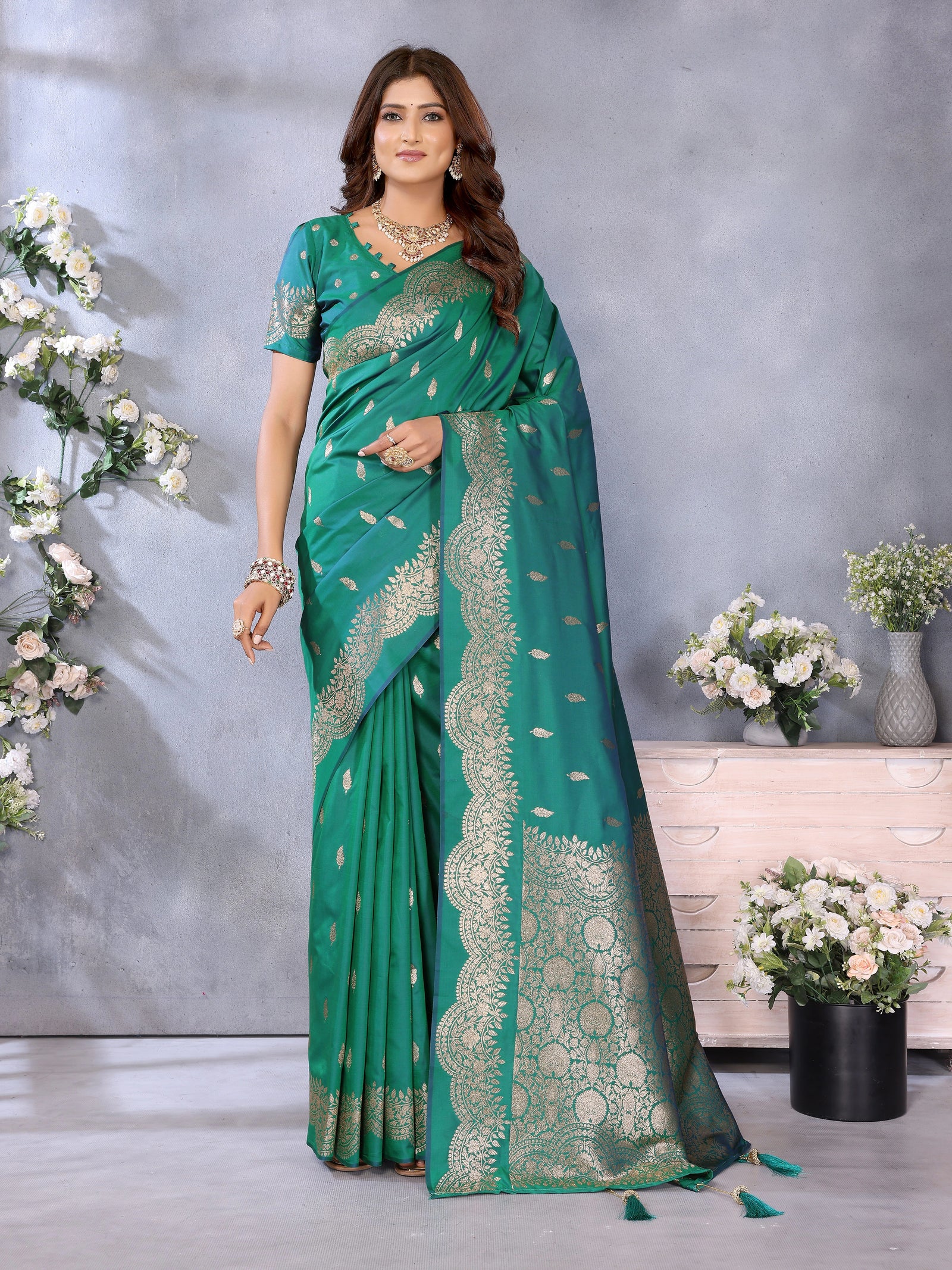 Woman wearing a green saree with white patterns in a decorated indoor setting.