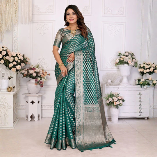 Woman wearing a green saree with a white background and decorative elements.