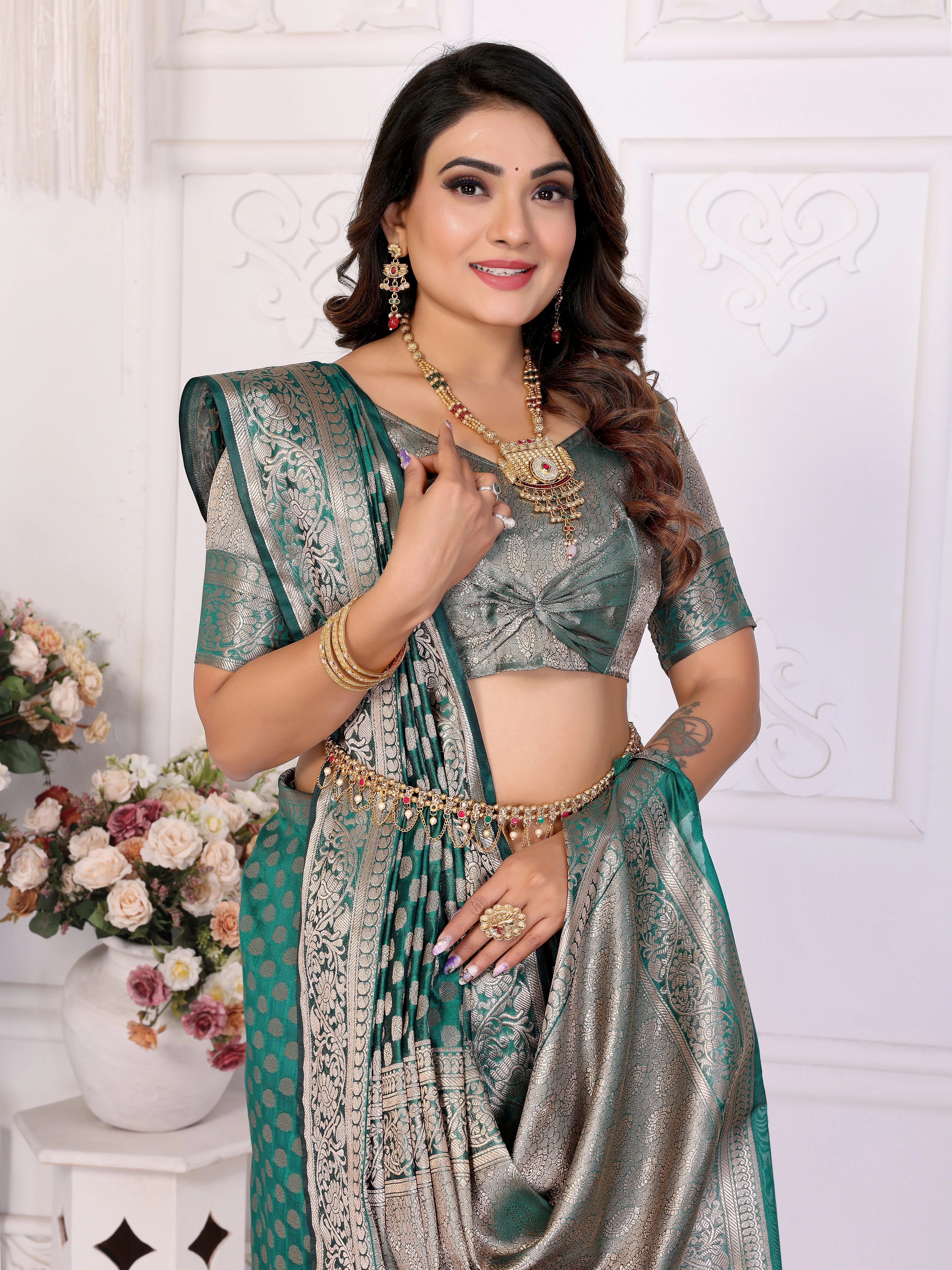 Woman in a traditional saree with jewelry against a white wall