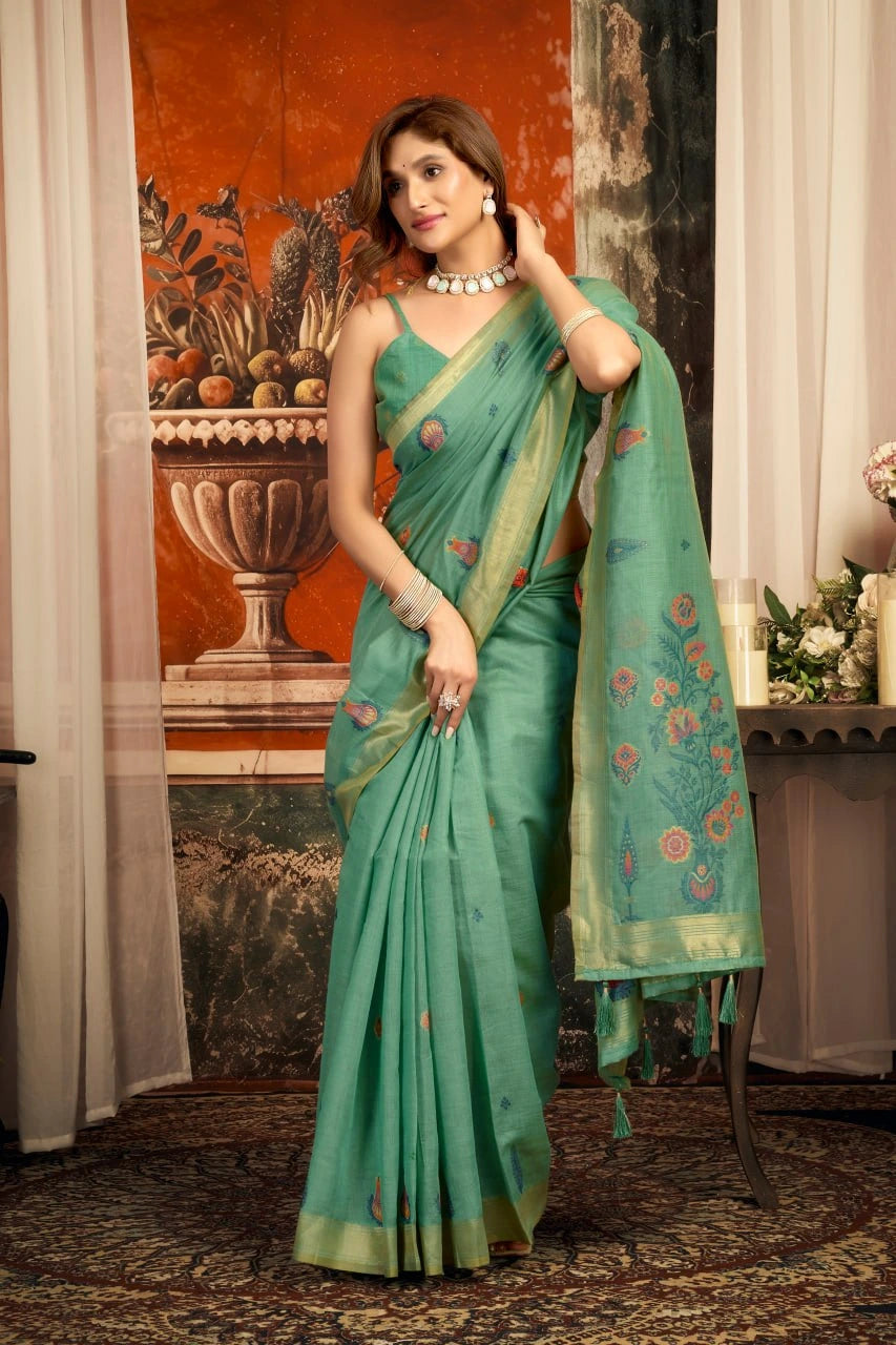Woman in a green saree with floral patterns in an indoor setting.
