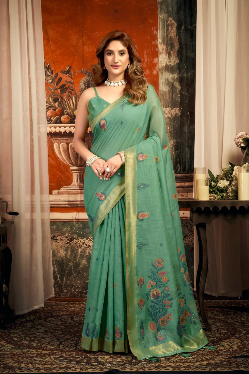 Woman wearing a green saree with floral patterns in an indoor setting.