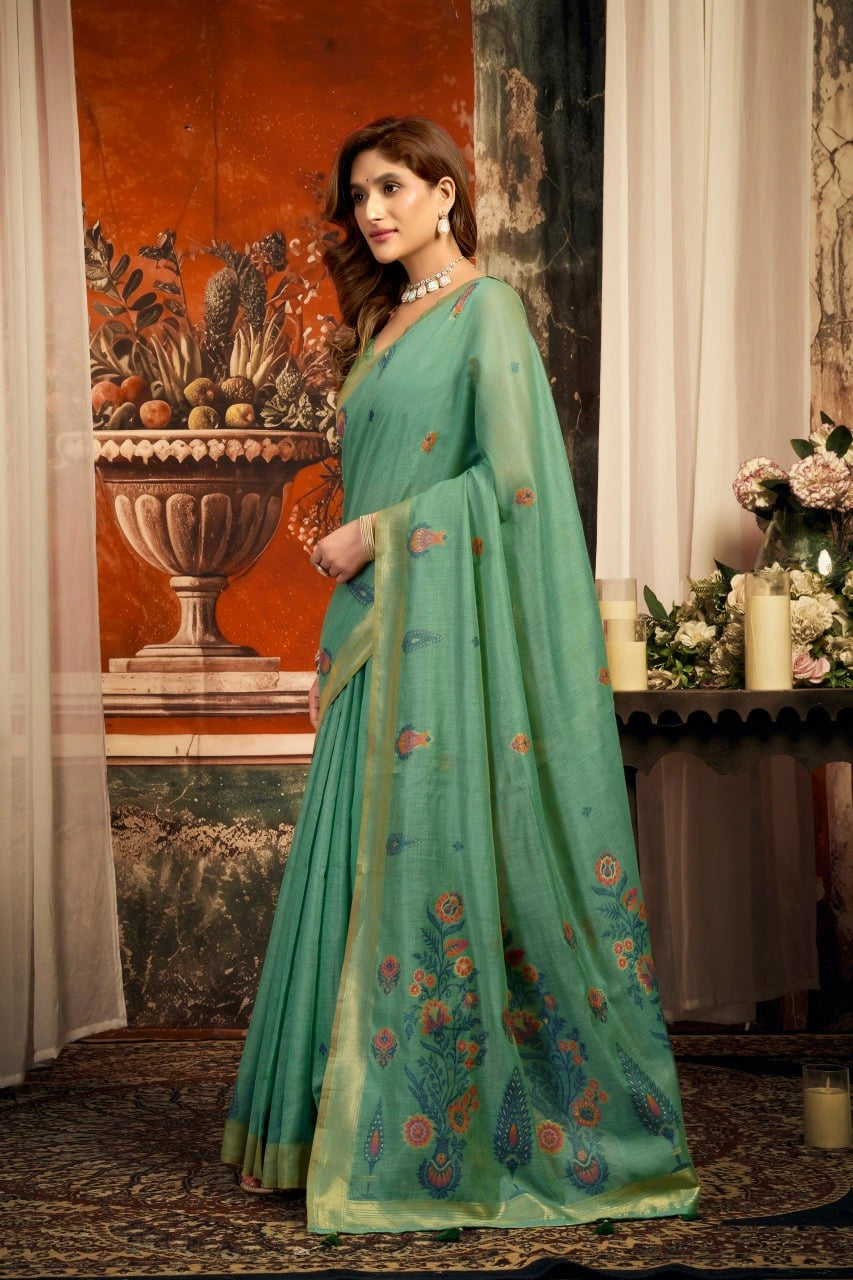 Woman wearing a green saree with floral patterns in an elegant indoor setting.