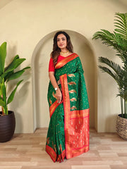 Woman wearing a green and red saree with a plant in the background