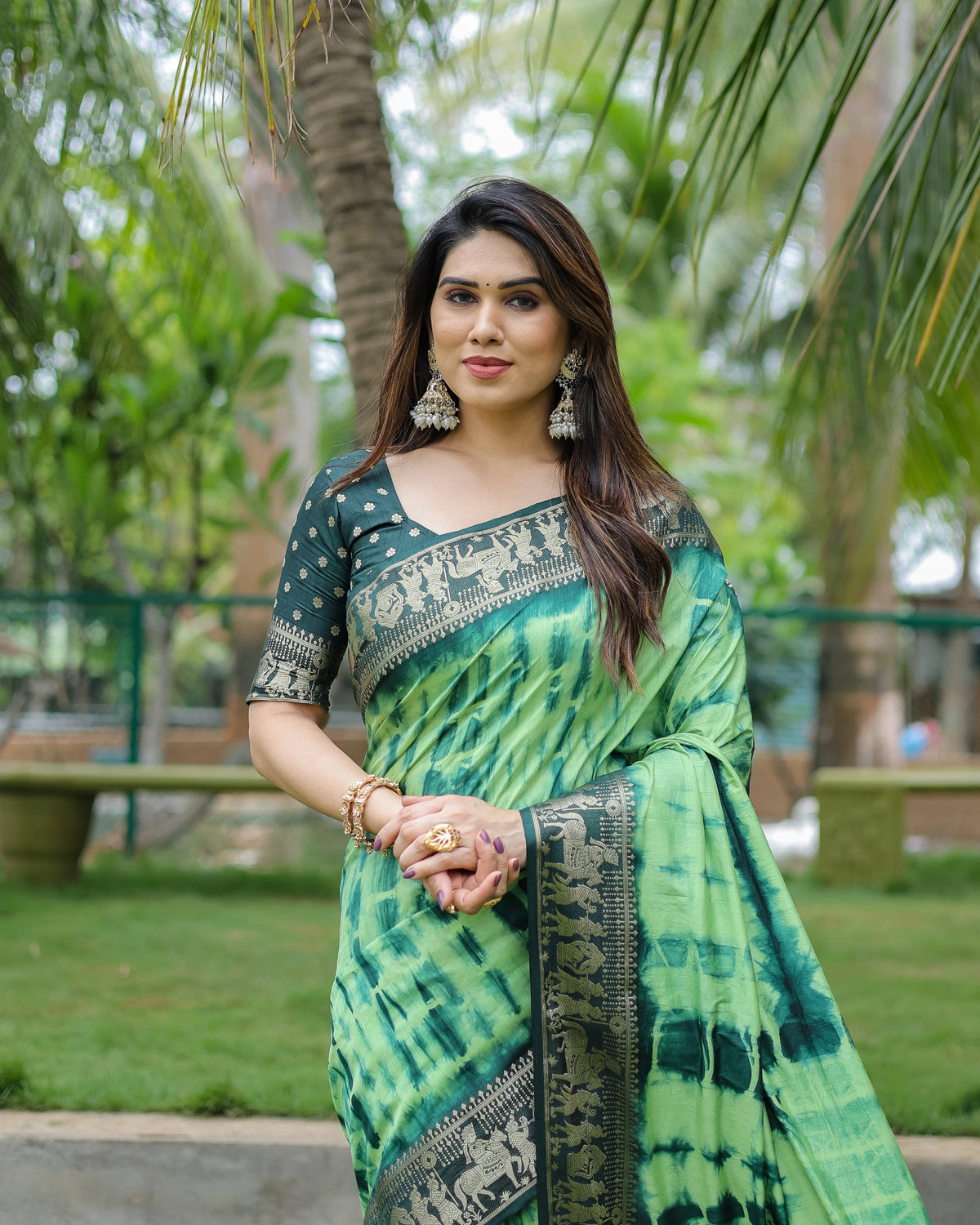 Woman wearing a green saree with a pattern in an outdoor setting