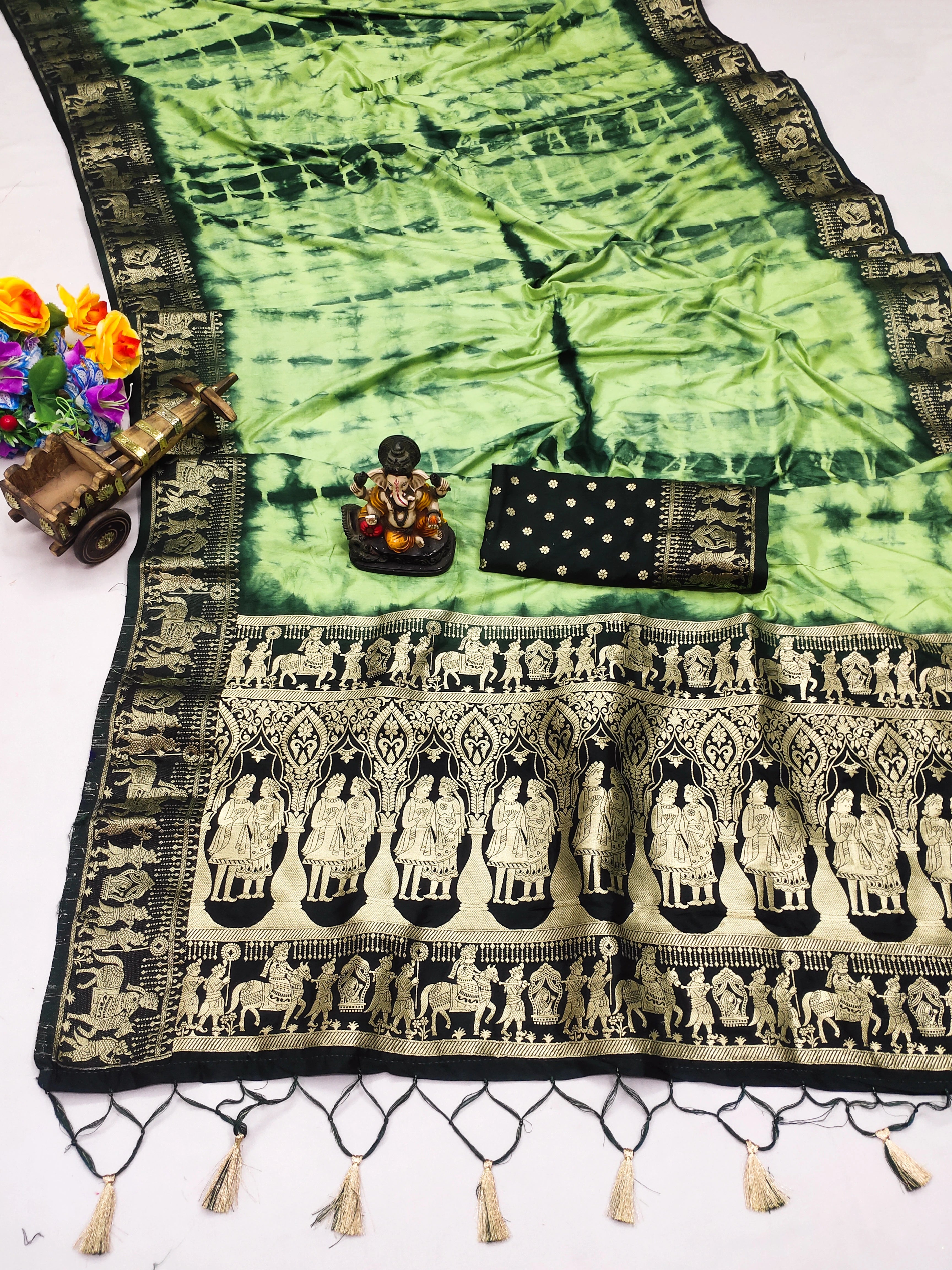 Green and black patterned fabric with tassels and a small statue on a white background