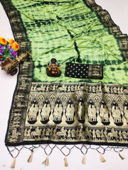 Green and black patterned fabric with tassels and a small statue on a white background