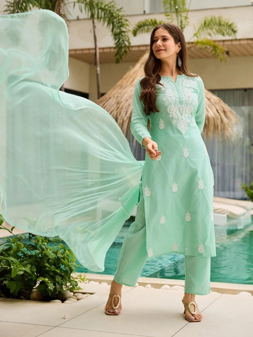 Woman in a light green traditional outfit by a poolside