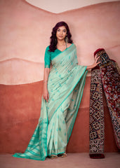 Woman in a light green saree with a pink background